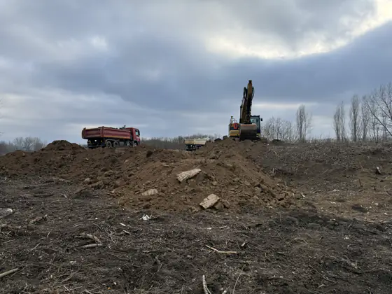 Kotrógép sziluettje a depónia tetején