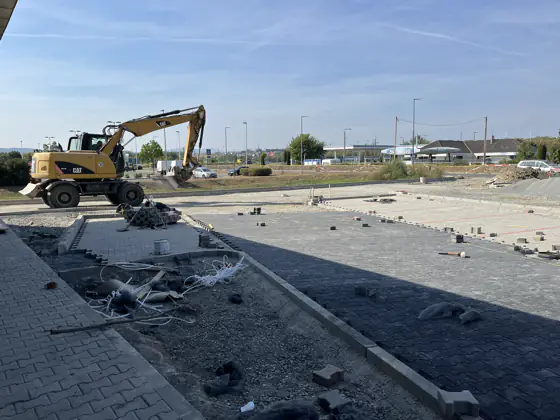 Kotrógép a készülő térburkolat mellett