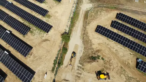 Épülő napelempark, földmunkagéppel a panelsorok között